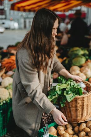 A woman picking fresh vegetables at an outdoor market in Erfurt, Germany.